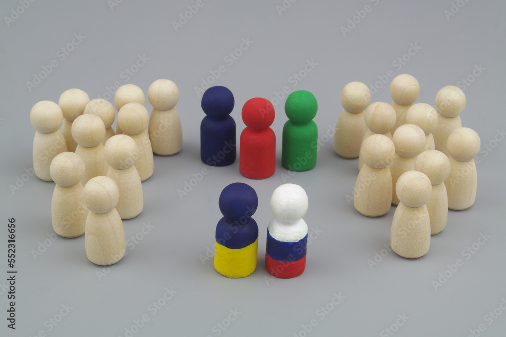 Wooden people figures are divided into two parts, and leaders is painted in colors of Ukrainian and Russian flags with international mediators. Peace between Russia and Ukraine concept. 
