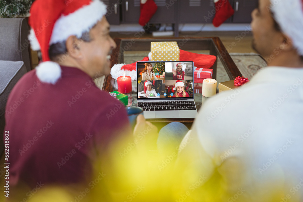 Senior biracial man and his adult son having christmas video call with diverse people
