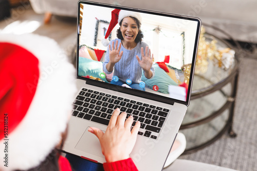 Caucasian woman having christmas video call with african american woman