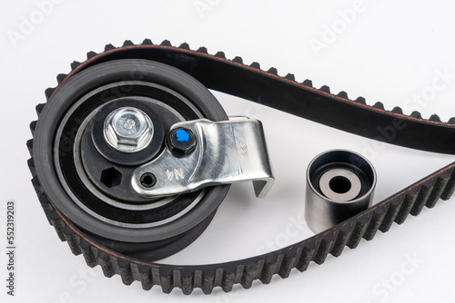 Close up repair kit: Timing belt with rollers, Tensioner pulley, Deflection pulley, Two rollers, Water pump and bolts on white background. Automobile spare part photo