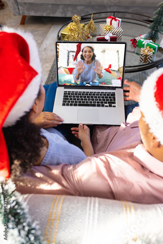 Biracial couple with santa hats having video call with happy biracial woman