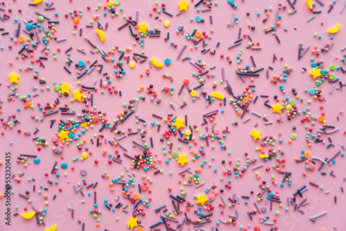 Top view of colorful sprinkles on pink background.
