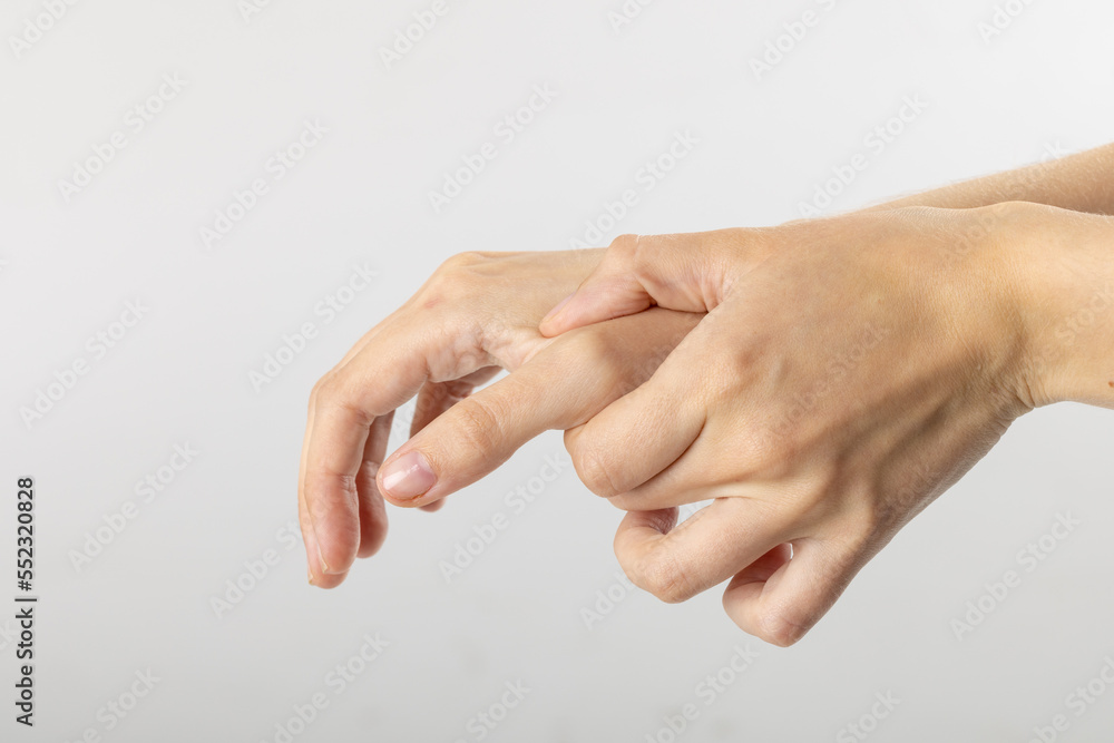 Close up of hands of caucasian woman massaging her thumb on white background with copy space Close up of hands of caucasian woman massaging her thumb on white background with copy space