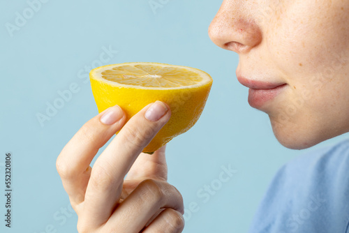 Close up of caucasian woman holding lemon on blue background