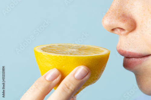 Close up of caucasian woman holding lemon on blue background