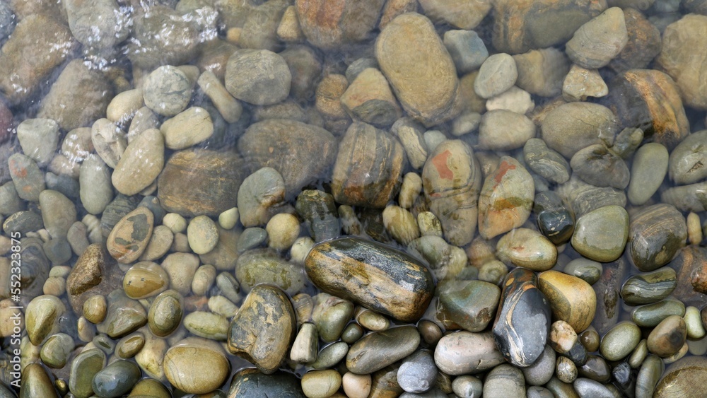rounded texture stones in transparent water as a natural background, stone space of a sea or river bank in a small amount of water, tide-turned cobblestones as a banner full frame rounded texture stones in transparent water as a natural background, stone space of a sea or river bank in a small amount of water, tide-turned cobblestones as a banner full frame