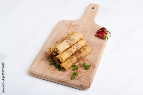 Spring roll stuffed with chicks with parsley paper on a piece photo