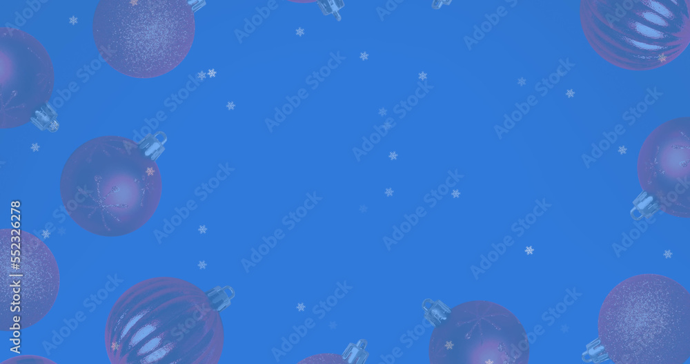 Fototapeta premium Image of snow falling over christmas bauble decorations on blue background