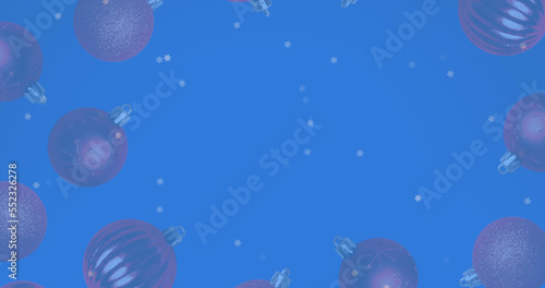Image of snow falling over christmas bauble decorations on blue background