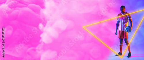 African american male with ball by illuminated triangle standing over pink smoky background
