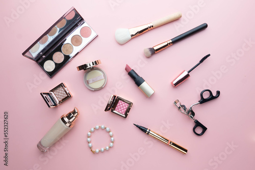 Top view of beauty cosmetic makeup accessories on pink background. Fashion woman make up product, brushes, lipstick, powder, foundation collection.