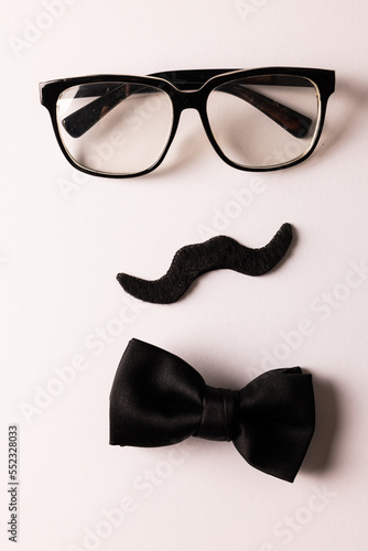 Composition of fake moustache with glasses and bow tie on white background with copy space