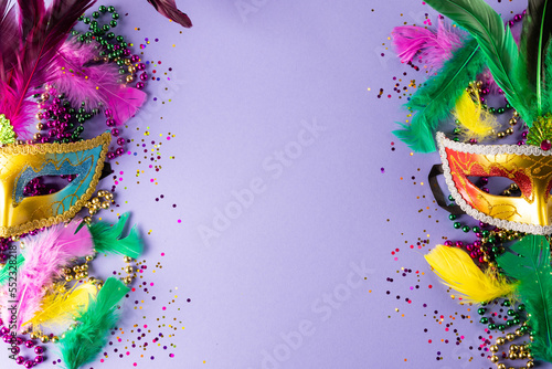 Photographie Colourful mardi gras beads, feathers and carnival masks on blue background with