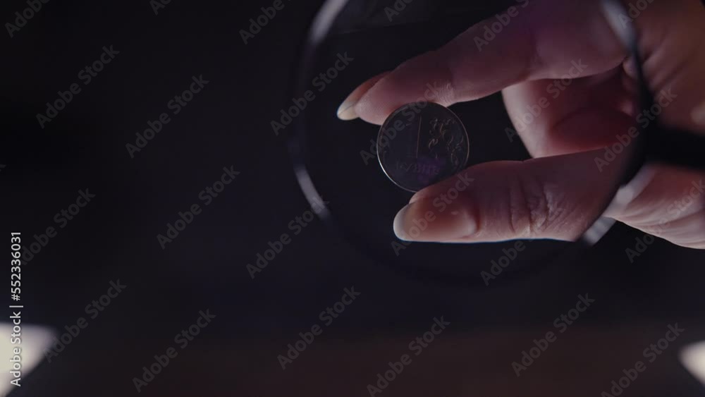 examination of a 2 euro coin under a magnifying glass on a black ...