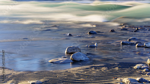 Small pebbles on the surface of the water, in a mountain river with a strong current.
And pretty ripples in the sand at the water's edge. Long exposure photo.
Southern Alps, France.