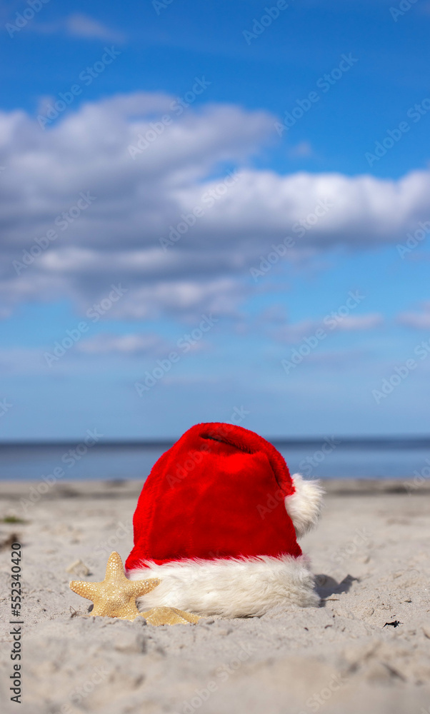 Santa Claus hat and starfish on the sandy beach Santa Claus hat and starfish on the sandy beach