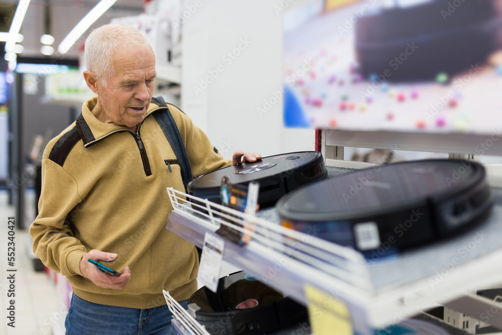 elderly man choosing robot vacuum cleaner in showroom of electrical appliance store elderly man choosing robot vacuum cleaner in showroom of electrical appliance store