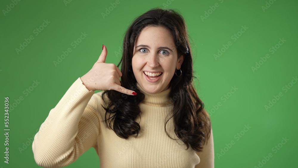 Portrait of smiling happy young woman 20s smiling and giving call me gesture with hands isolated on green screen background. Portrait of smiling happy young woman 20s smiling and giving call me gesture with hands isolated on green screen background.