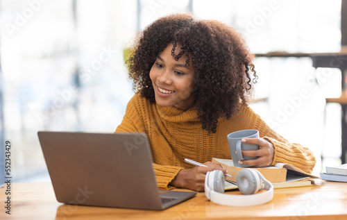 Young beautiful african student girl working, learning in computer and device studying online.