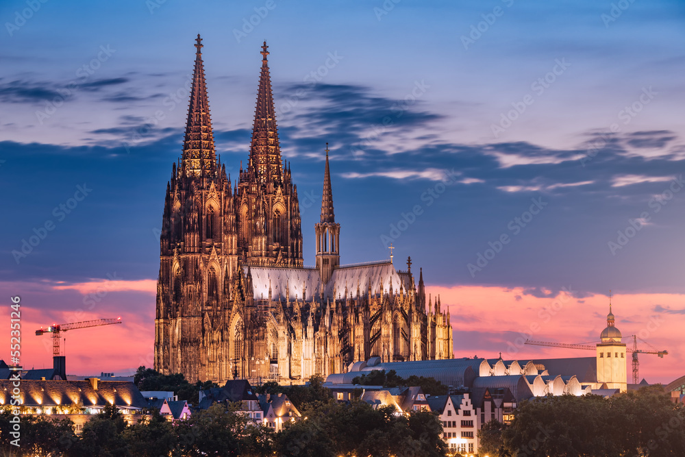 Distant view of the city of Cologne at evening after sunset with the cathedral as an architectural dominant. Real estate and urban life in Germany.