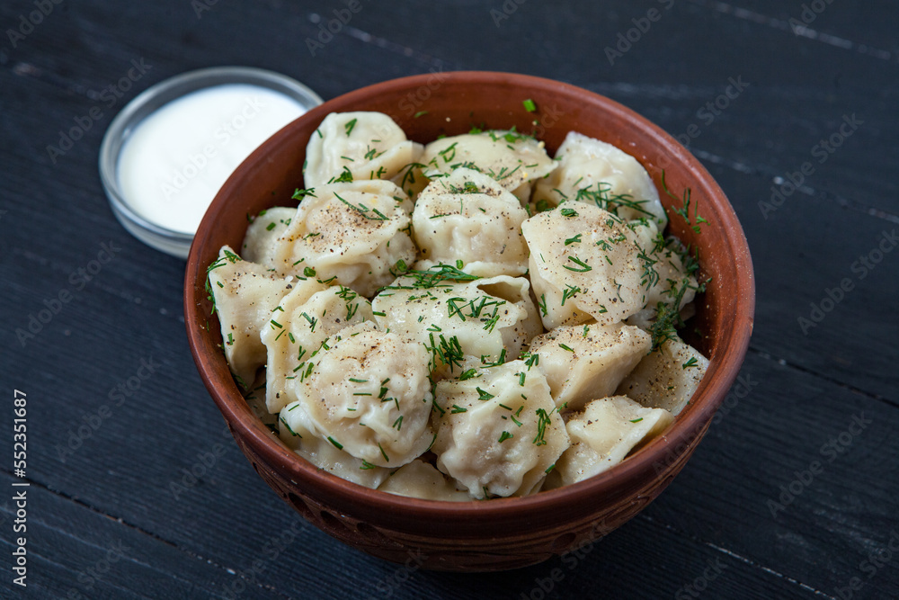 Traditional russian pelmeni or ravioli, dumplings with meat on wood black background. Russian food and russian kitchen concept. Traditional russian pelmeni or ravioli, dumplings with meat on wood black background. Russian food and russian kitchen concept.