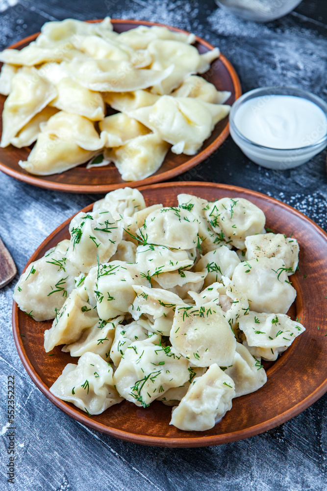 Traditional russian pelmeni or ravioli, dumplings with meat on wood black background. Russian food and russian kitchen concept.