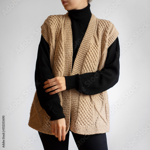 Woman wearing sweater vest, black turtleneck and black trousers on white background