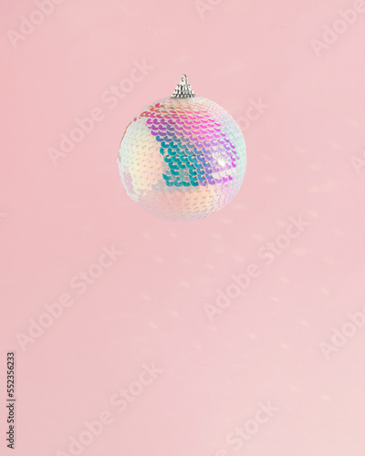 Sparkly disco Christmas bauble ornament on a soft pink background. New Year's countdown moments. Celebration concept idea