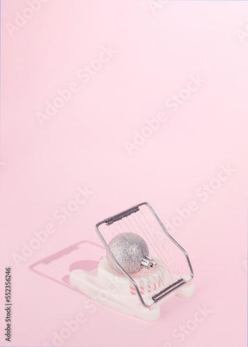 Sparkly silver Christmas ornament in egg cutter. Soft pink background. New Year's concept design idea. Abstract holidays moments in December