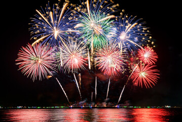 Amazing beautiful colorful fireworks display on celebration night, showing on the sea beach with multi color of reflection on water.