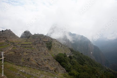 Panoramic view of the ancient Inca city of Machu Picchu in the Sacred Valley in Peru with the Huayna Picchu mountain in the background covered by clouds.