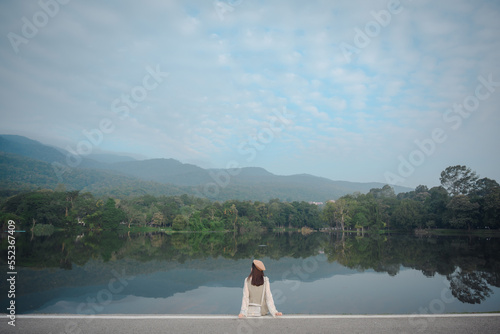 Asian female tourists Sitting and looking at the natural view at Ang Kaew Reservoir, Chiang Mai University. Chiang Mai Province concept of women traveling in Thailand photo