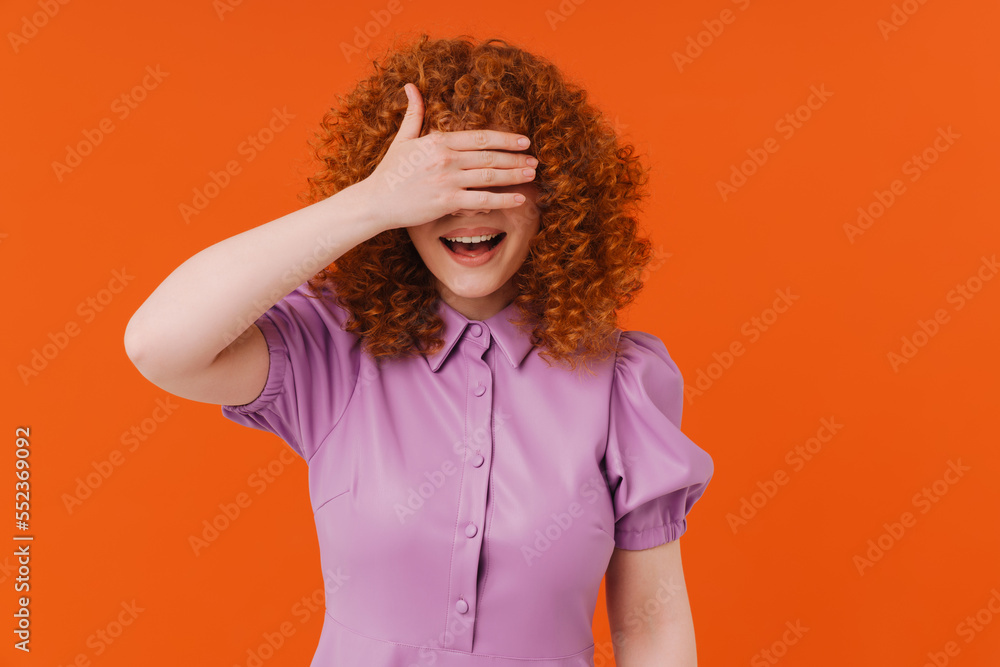 Cheerful redhead girl covering mouth with hands isolated Cheerful redhead girl covering mouth with hands isolated
