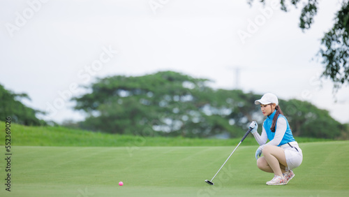 golfer asian women sitting hold golf club checking fairway and teeing golf in golf tournament competition at golf course,