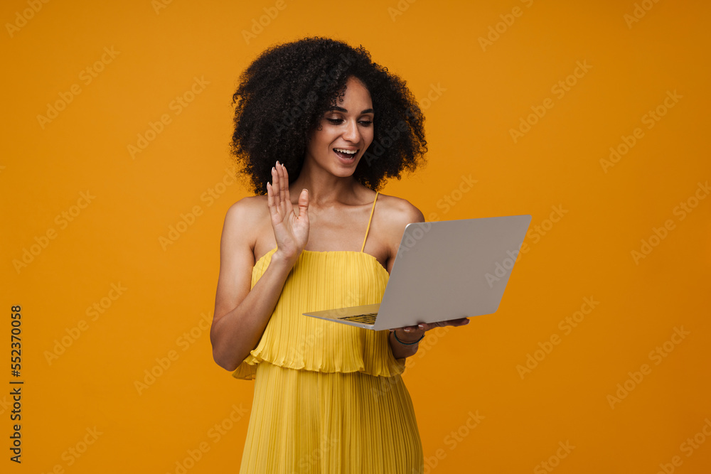 Cheerful young african woman talking by video call on laptop and waving isolated Cheerful young african woman talking by video call on laptop and waving isolated