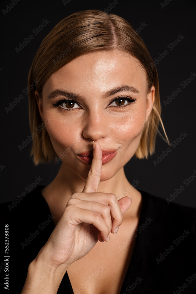 Young blond woman showing silence gesture at camera Young blond woman showing silence gesture at camera