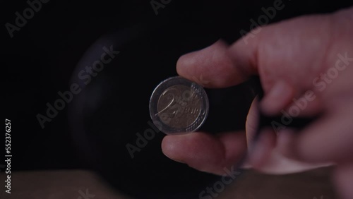coin authenticity check, 2 euro coin under a magnifying glass on a black background, close-up photo