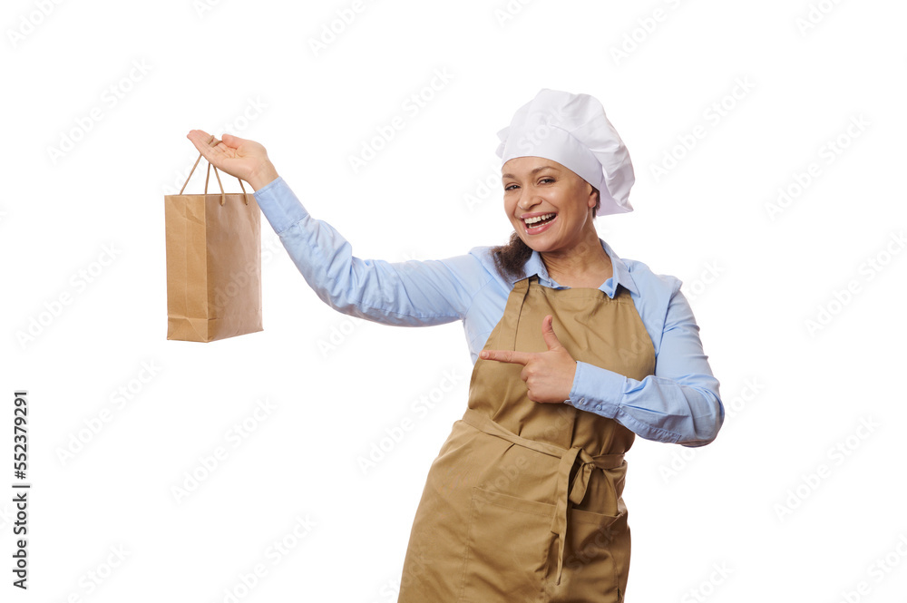 Happy African American woman waitress, chef confectioner wearing beige apron, showing on camera a disposable eco paper bag with healthy take out fresh food, white background. Delivery service concept Happy African American woman waitress, chef confectioner wearing beige apron, showing on camera a disposable eco paper bag with healthy take out fresh food, white background. Delivery service concept