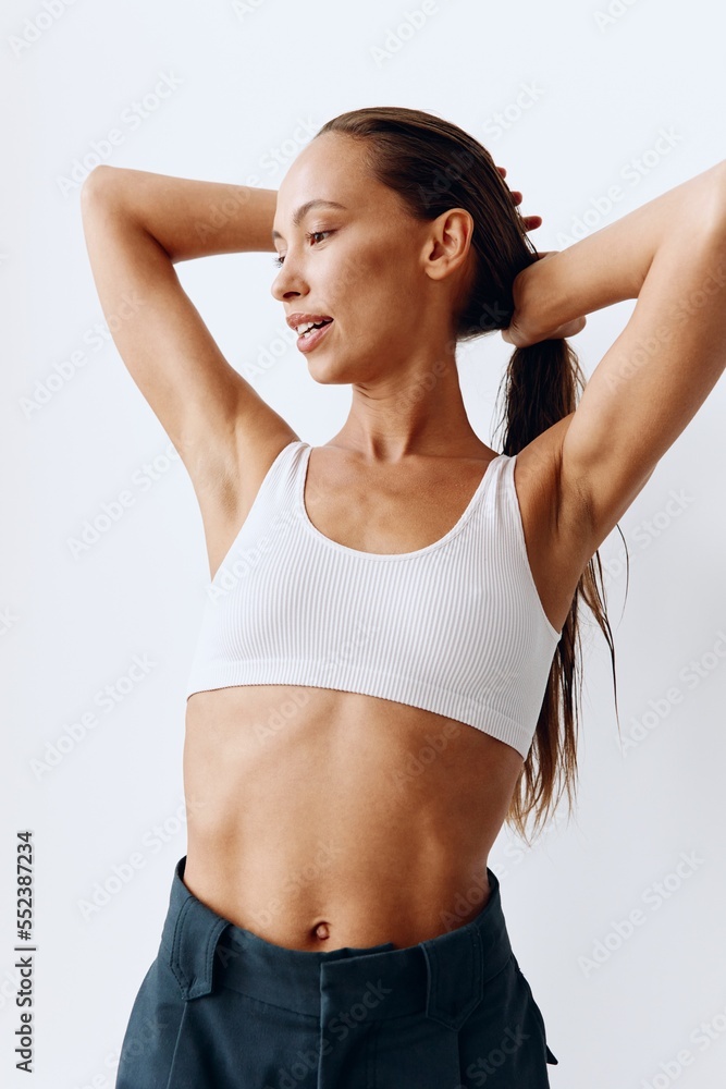 Portrait of a woman with a beautiful body and tanned skin posing in white on a white background in her studio in her home clothes fixing her hair and smiling beautifully with her teeth Portrait of a woman with a beautiful body and tanned skin posing in white on a white background in her studio in her home clothes fixing her hair and smiling beautifully with her teeth