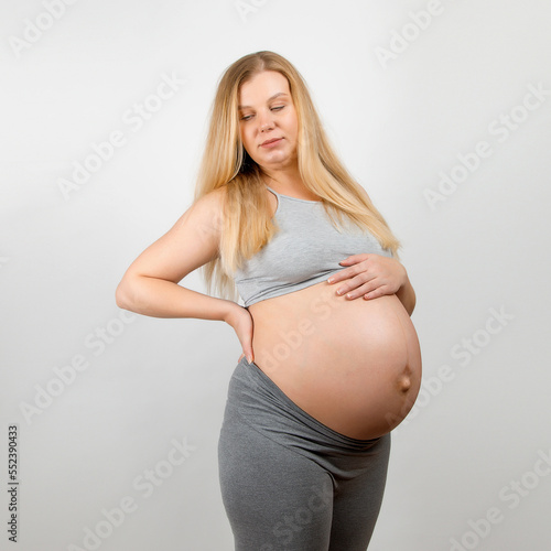 A pregnant girl, on a gray background. Big stomach, back pain. Free Download A pregnant girl, on a gray background. Big stomach, back pain. - GFXLoad