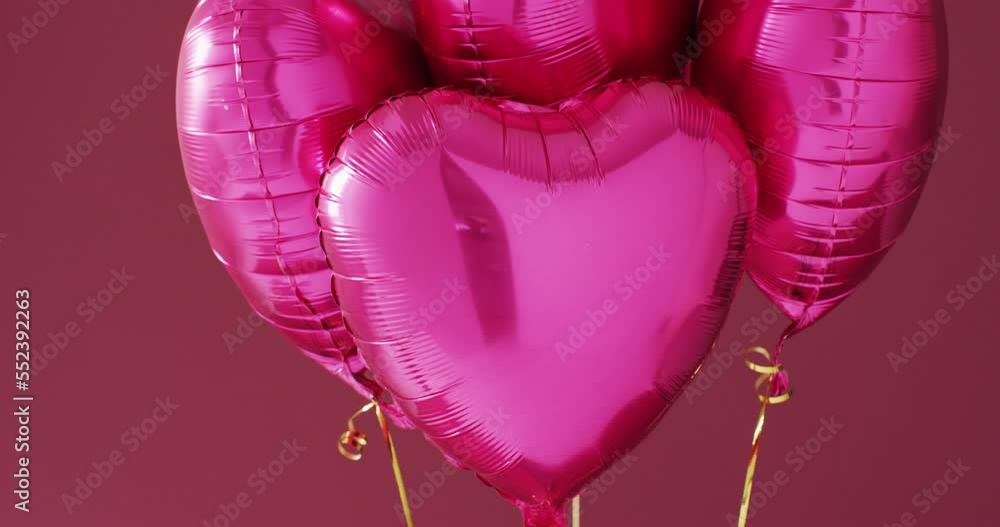 Video of four shiny pink heart shaped balloons floating on pink ...