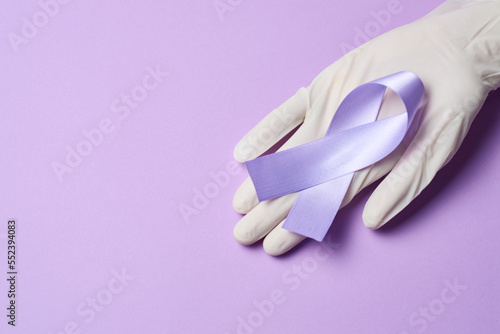 Doctor holding purple ribbon, world cancer day february 4th, on flat lay purple.