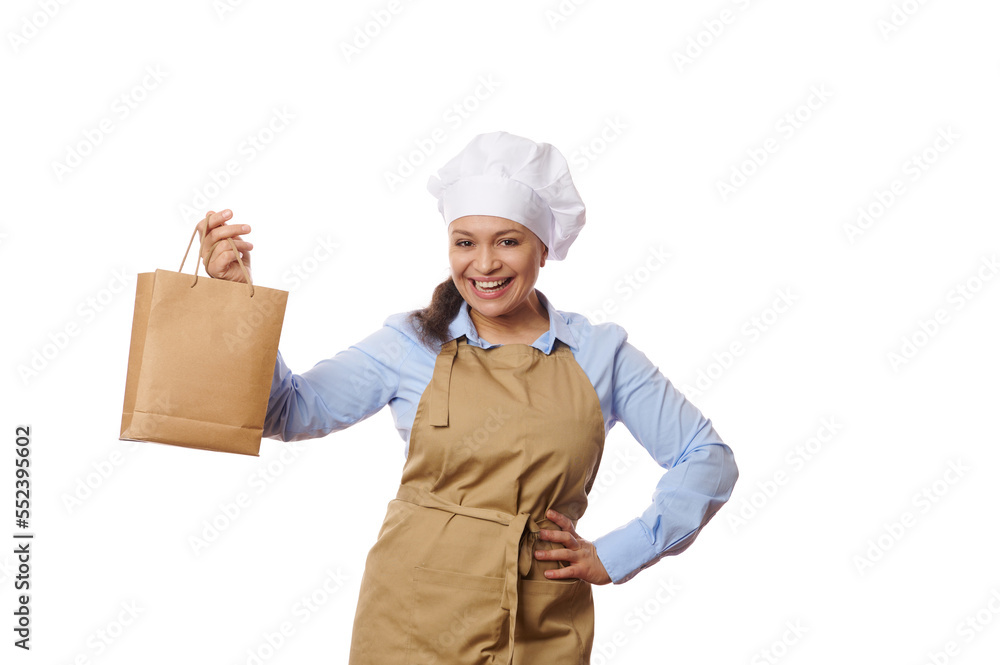 Beautiful Hispanic woman waitress or chef pastry in beige apron, holding disposable eco paper bag with takeaway fresh food and hot beverage, isolated on white background. Home delivery service concept Beautiful Hispanic woman waitress or chef pastry in beige apron, holding disposable eco paper bag with takeaway fresh food and hot beverage, isolated on white background. Home delivery service concept