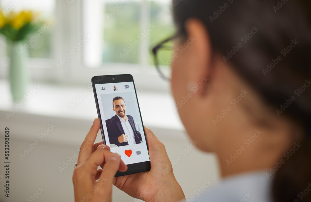 Young woman is going to give like to man's photo in mobile dating app on smartphone screen. Single woman looking for love and relationship online. Searching for romantic partner in social app concept.