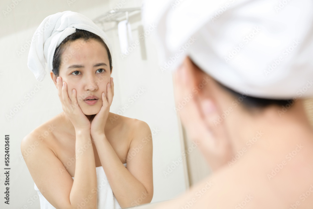 Problem skin. Concerned young asian women popping pimple on cheek while standing near mirror in bathroom. young asian women with acne Problem skin. Concerned young asian women popping pimple on cheek while standing near mirror in bathroom. young asian women with acne