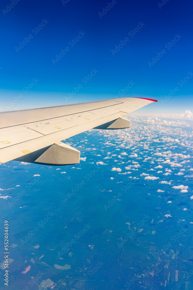 Fototapeta premium View from the airplane window at a beautiful cloudy sky and the airplane wing