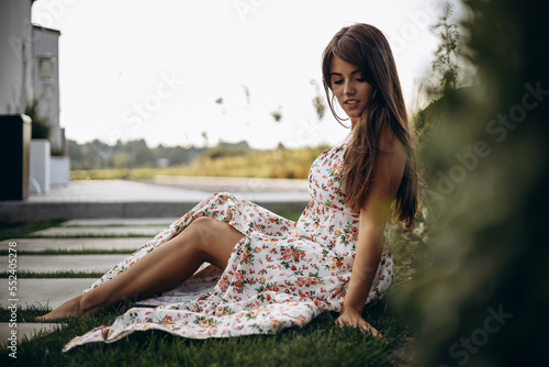 Attractive woman in summer dress sitting on ground