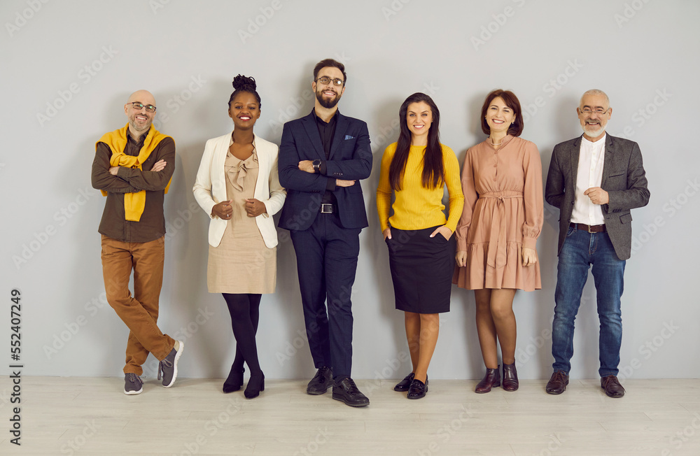 Fototapeta premium Group portrait of smiling diverse businesspeople pose on grey wall background in office. Happy multiracial colleagues or coworkers show unity at workplace. Employment or recruitment concept.