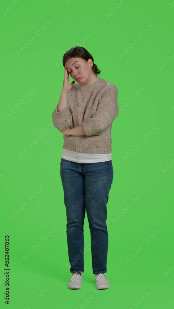 Vertical video: Front view of female model suffering from headache over green screen backdrop, dealing with painful migraine. Unwell person standing over full body greenscreen, isolated copyspace in Vertical video: Front view of female model suffering from headache over green screen backdrop, dealing with painful migraine. Unwell person standing over full body greenscreen, isolated copyspace in