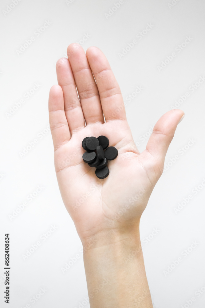 a woman holds a black sorbent pills. detox concept a woman holds a black sorbent pills. detox concept